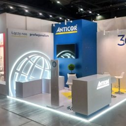 Brand Creation Mariusz Lenart Paweł Lebica Dominik Kołek Spółka Jawna - Stoisko targowe firmy Anticor z podświetlanym logo, ekranem i motywem 30-lecia, widoczne krzesła barowe i dekoracyjna roślina.