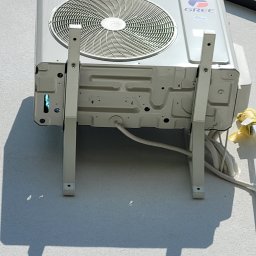 SOFTLIGHT Fotowoltaika & Klimatyzacja - Zewnętrzna jednostka klimatyzacji Gree zamontowana na białej elewacji budynku, widoczna drabina z żółtymi osłonami na szczeblach.