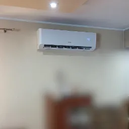 Biała klimatyzacja marki Gree zamontowana na ścianie w jasnym pomieszczeniu, z widocznym wyświetlaczem temperatury.