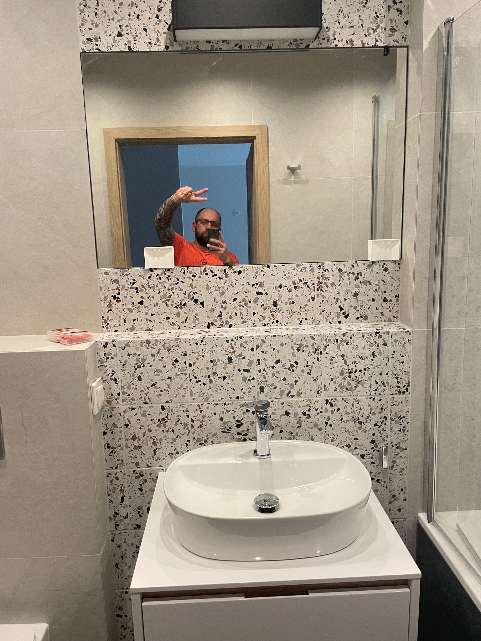 Nowoczesna łazienka z umywalką nablatową i mozaiką w stylu lastryko, odbicie w lustrze osoby robiącej zdjęcie.