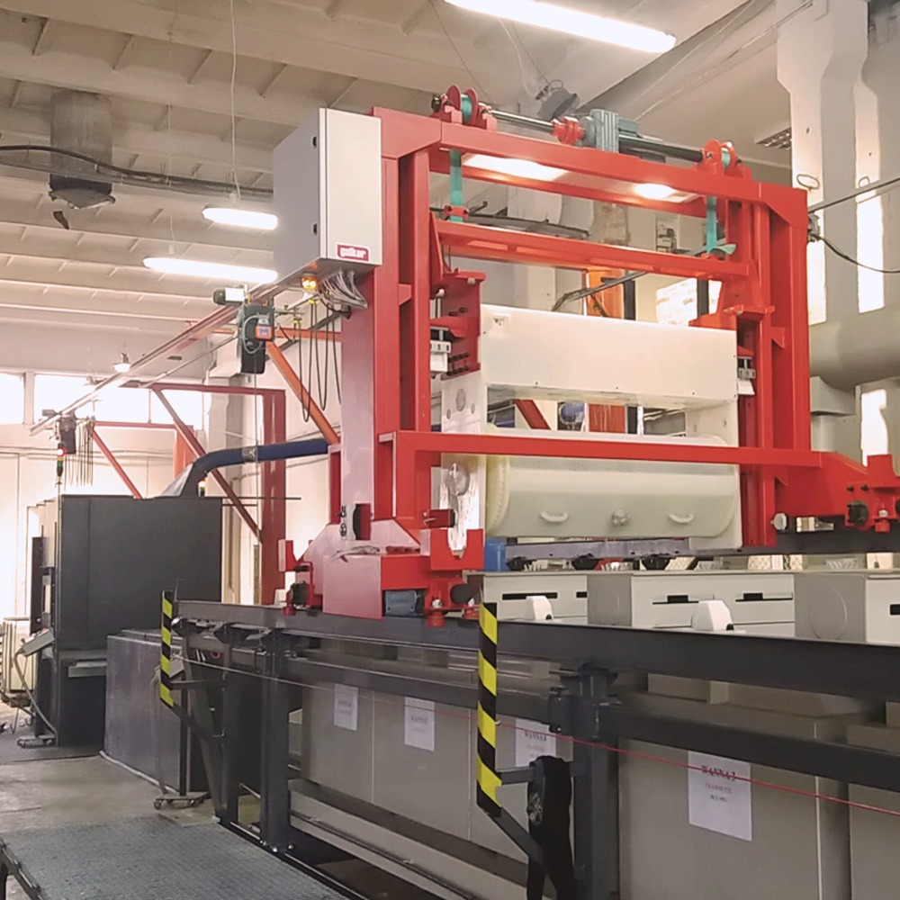 Automatyczna linia do cynkowania wysokotemperaturowego, z czerwonymi elementami konstrukcyjnymi i białymi zbiornikami, zainstalowana w hali produkcyjnej.