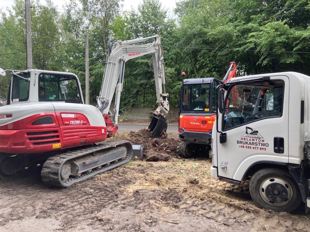 Dwa mini-koparki Takeuchi i Kubota oraz samochód dostawczy Helanton Brukarstwo na placu budowy z błotnistym podłożem, w tle drzewa.