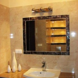 WM-Bud - Wykończona łazienka z beżowymi płytkami, lustrem w czarnej ramie i białymi wazonami dekoracyjnymi na blacie