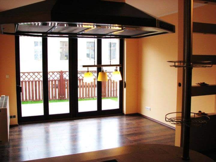 Jasne wnętrze po remoncie w Oleśnicy: parkiet, duże okno tarasowe z widokiem na ogród i świeżo pomalowane ściany w ciepłym odcieniu.