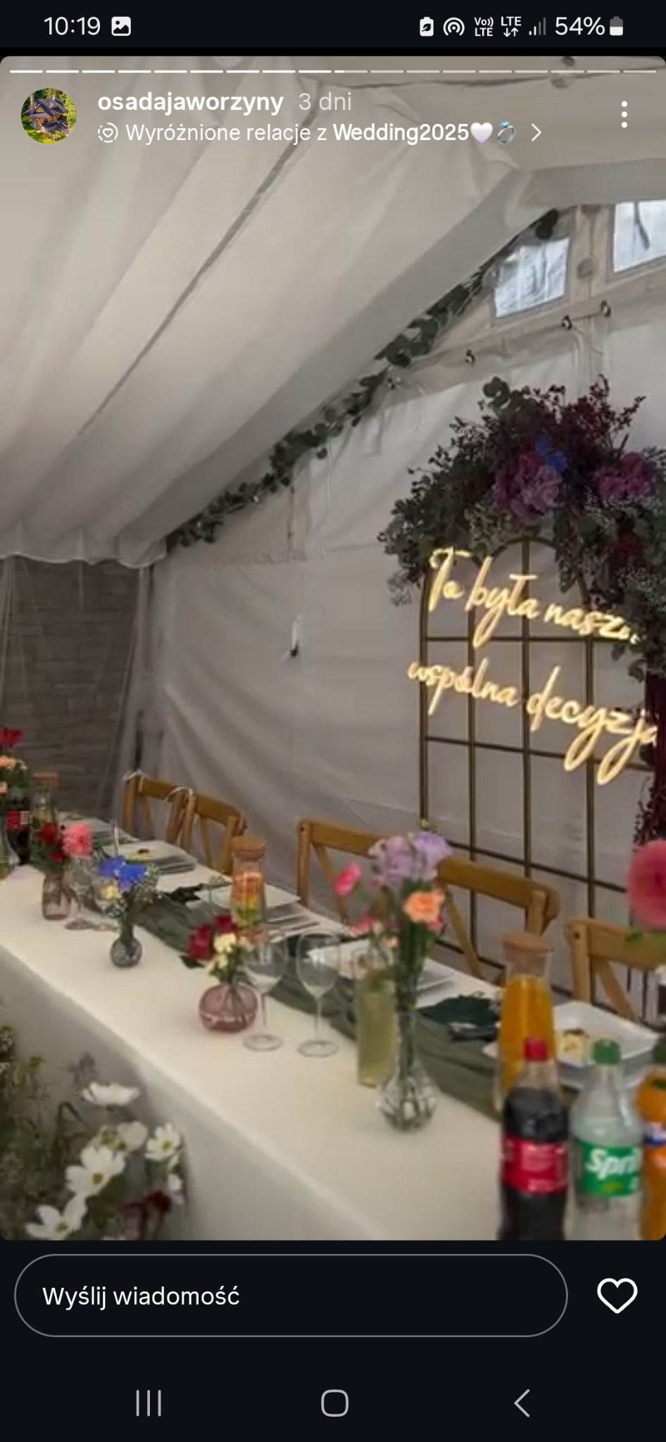 Uroczysty stół w namiocie, dekoracje kwiatowe, neonowy napis 'To była nasza wspólna decyzja'. Przygotowania do wesela, detale wystroju.