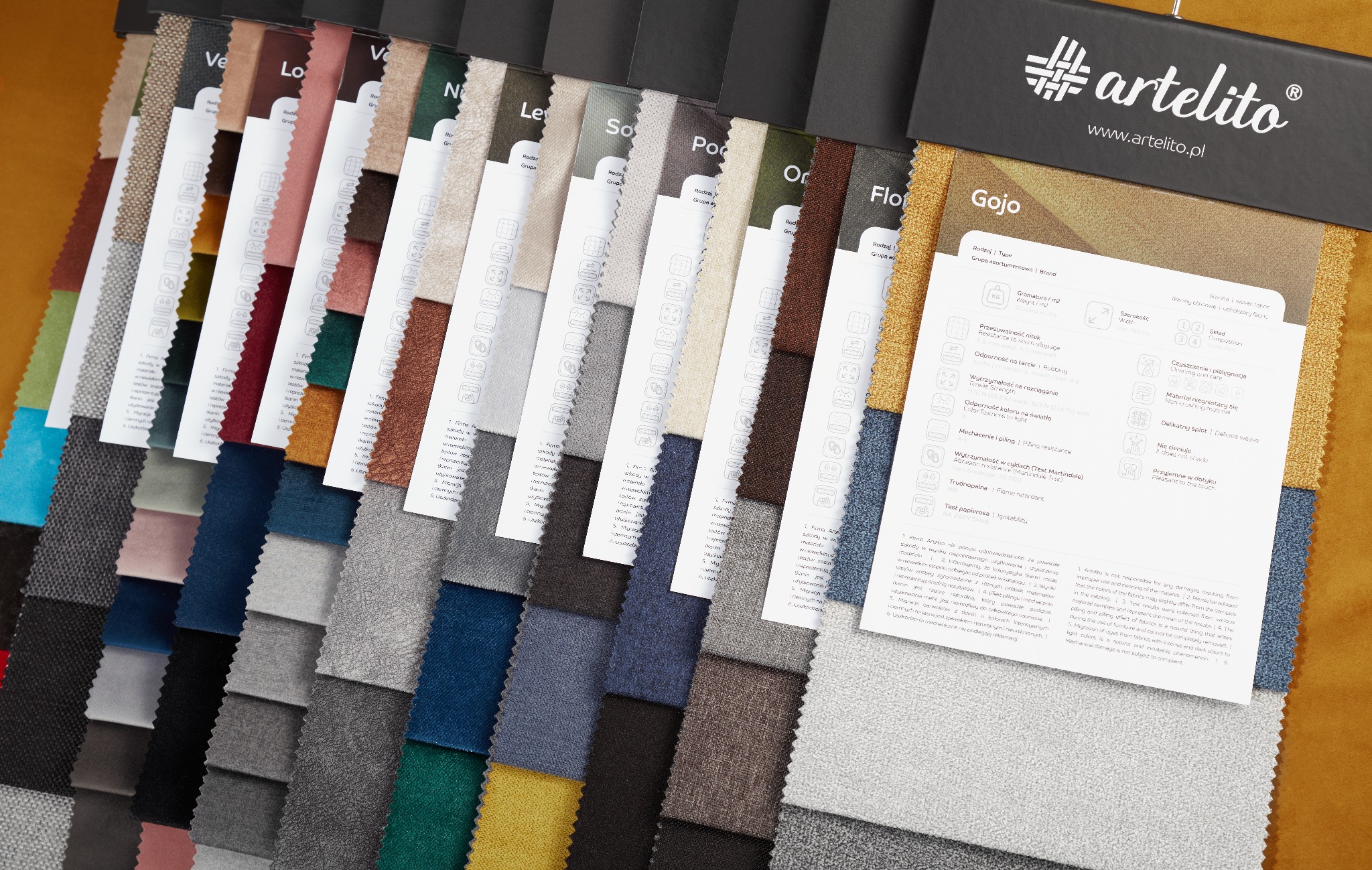 Katalog próbek tkanin obiciowych z informacjami o właściwościach, prezentujący różnorodne kolory i tekstury materiałów.