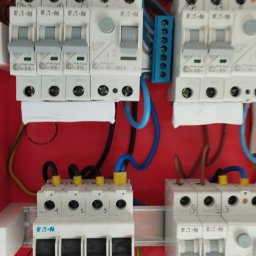 ELROM Firma Elektryczna Roman Oźmina - Rozdzielnica elektryczna Eaton z bezpiecznikami i przewodami w kolorowej obudowie. Widoczne szczegóły podłączeń i oznaczenia na elementach.