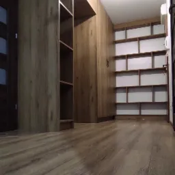 Wnętrze garderoby z zabudową drewnianą na wymiar, obejmującą szafę wnękową z półkami i panele ścienne, widok z perspektywy podłogi z widoczną strukturą drewna.