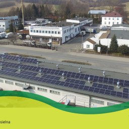 Zielona Energia Sp. z o.o. - Panele słoneczne na dachu budynku Okręgowej Spółdzielni Mleczarskiej w Jasienicy Rosielnej, widok z góry, w tle zabudowa miejscowości.