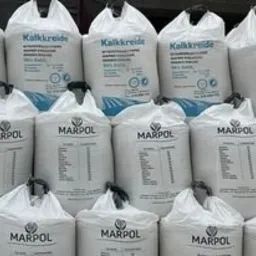 Stos białych worków z wapnem nawozowym marki Marpol, ułożonych piramidalnie, z widocznymi napisami i informacjami o składzie.