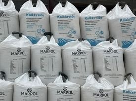 Stos białych worków z wapnem nawozowym marki Marpol, ułożonych piramidalnie, z widocznymi napisami i informacjami o składzie.