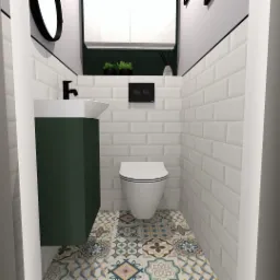 Kompaktowa łazienka z toaletą, umywalką na szafce w kolorze butelkowej zieleni, białe kafelki typu metro na ścianach, wzorzysta podłoga, czarne akcenty w postaci armatury i ramy lustra.