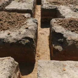 Wykopane rowy pod fundamenty z widoczną strukturą gleby, przygotowane do dalszych prac budowlanych.