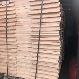 Stos drewnianych, składanych leżaków zabezpieczonych pasami transportowymi na palecie wewnątrz pojazdu dostawczego.