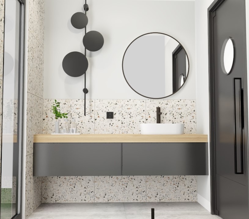 Nowoczesna łazienka z umywalką nablatową, szarą szafką pod umywalką z drewnianym blatem, okrągłym lustrem w czarnej ramie, ozdobną lampą z czarnymi kulami i drzwiami z okrągłym okienkiem.