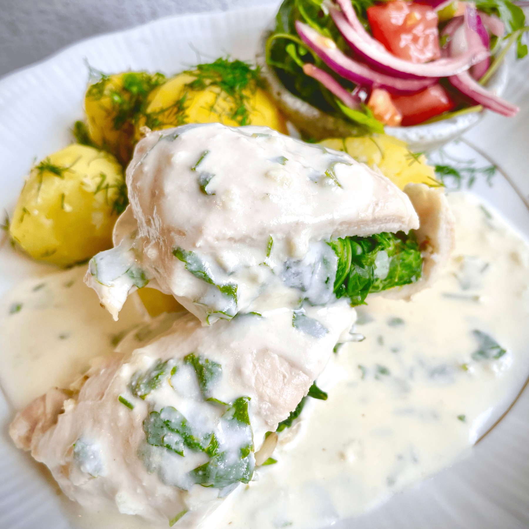 Danie z kurczaka ze szpinakiem i sosem śmietanowym, podane z ziemniakami posypanymi koperkiem i sałatką warzywną, przygotowane przez specjalistę od żywienia z Suchej Beskidzkiej.