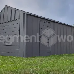 Szary garaż blaszany z drzwiami i bramą garażową, ustawiony na trawniku, z widocznym w tle domem i drzewami.