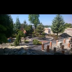 Visual Garden - Prace ogrodnicze w toku: układanie kamieni, sadzenie drzew i krzewów iglastych, widoczne rury do systemu nawadniania.