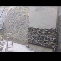 Visual Garden - Wykończenie ściany zewnętrznej kamieniem dekoracyjnym, widoczna drabina i częściowo wykonana elewacja z kamienia łupanego oraz kamienia warstwowego.