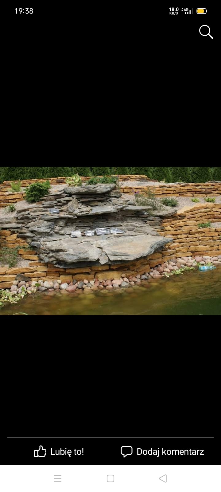 Ogród z oczkiem wodnym, kaskadą z kamieni i roślinami ozdobnymi.