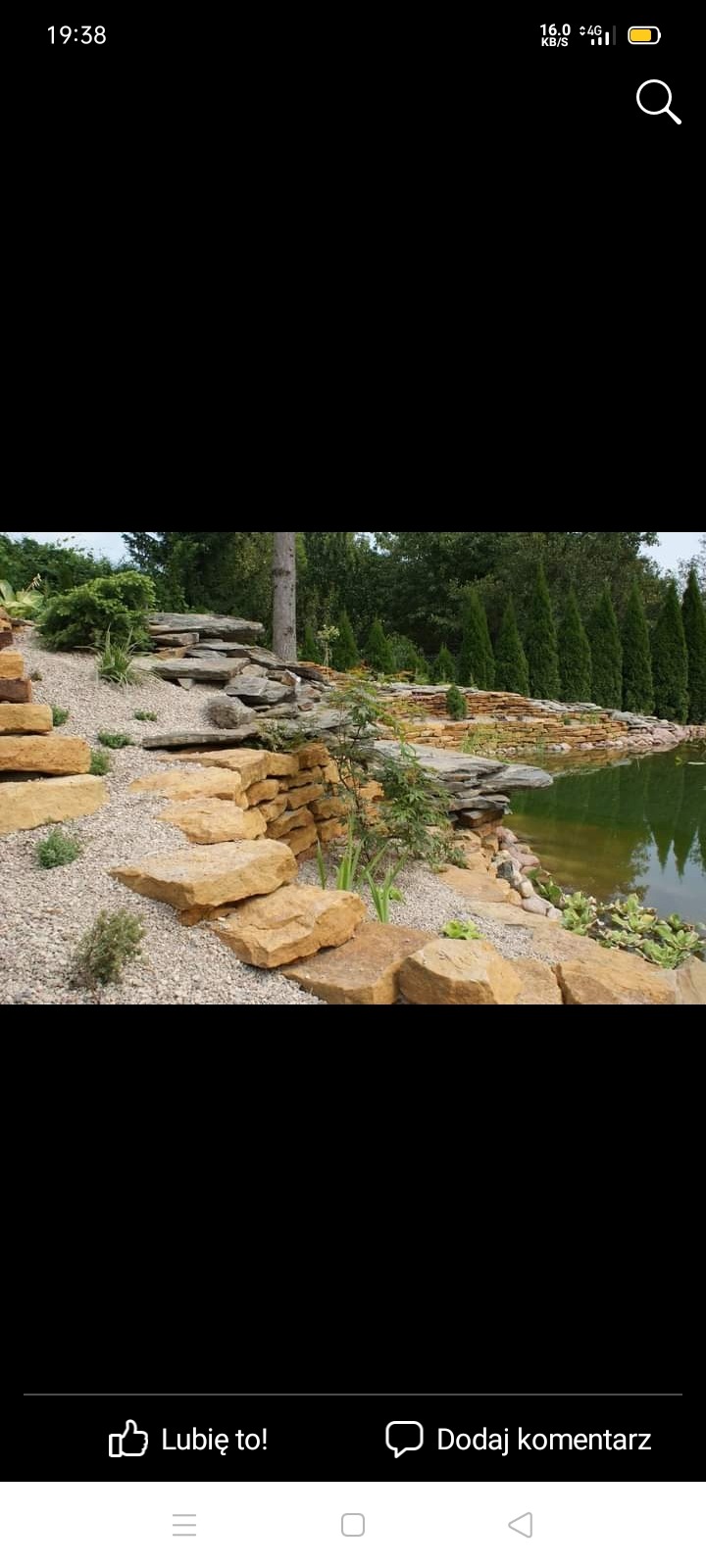 Ogród ze skalnymi schodami prowadzącymi do oczka wodnego otoczonego kamieniami i roślinnością.