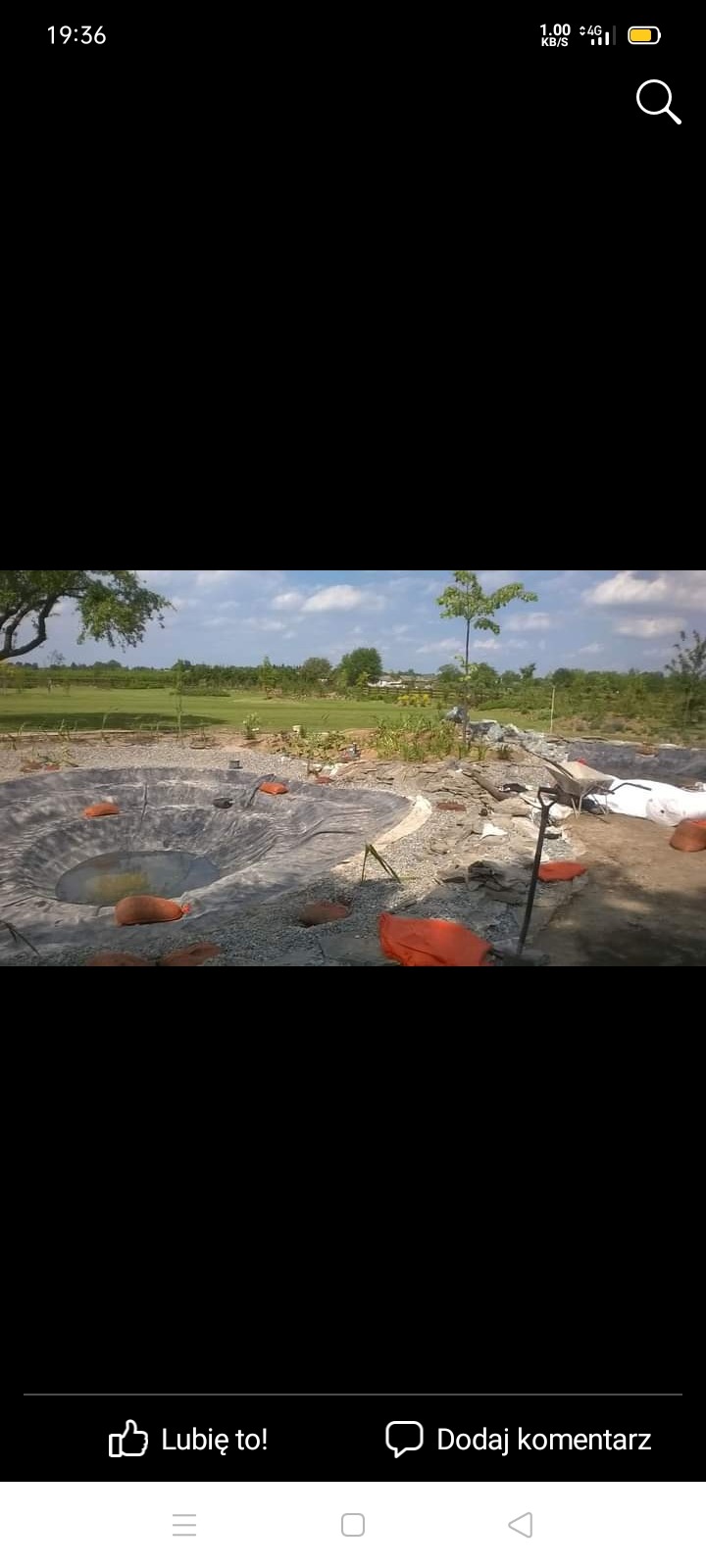 Wykopany dół pod budowę basenu ogrodowego z rozłożoną folią, otoczony gruzem i narzędziami na trawiastym terenie.