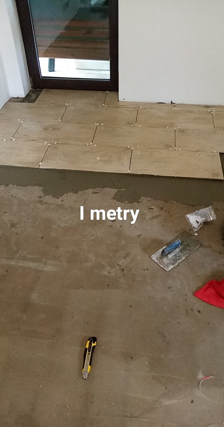 Układanie podłogi z drewnopodobnych płytek, widoczne krzyżyki dystansowe, szpachelka, nóż do tapet i zaprawa klejowa.