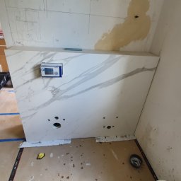 Instal-rem - Montaż umywalki z marmurowym blatem w trakcie prac wykończeniowych w Warszawie, widoczne otwory na instalację hydrauliczną i kontroler elektroniczny.