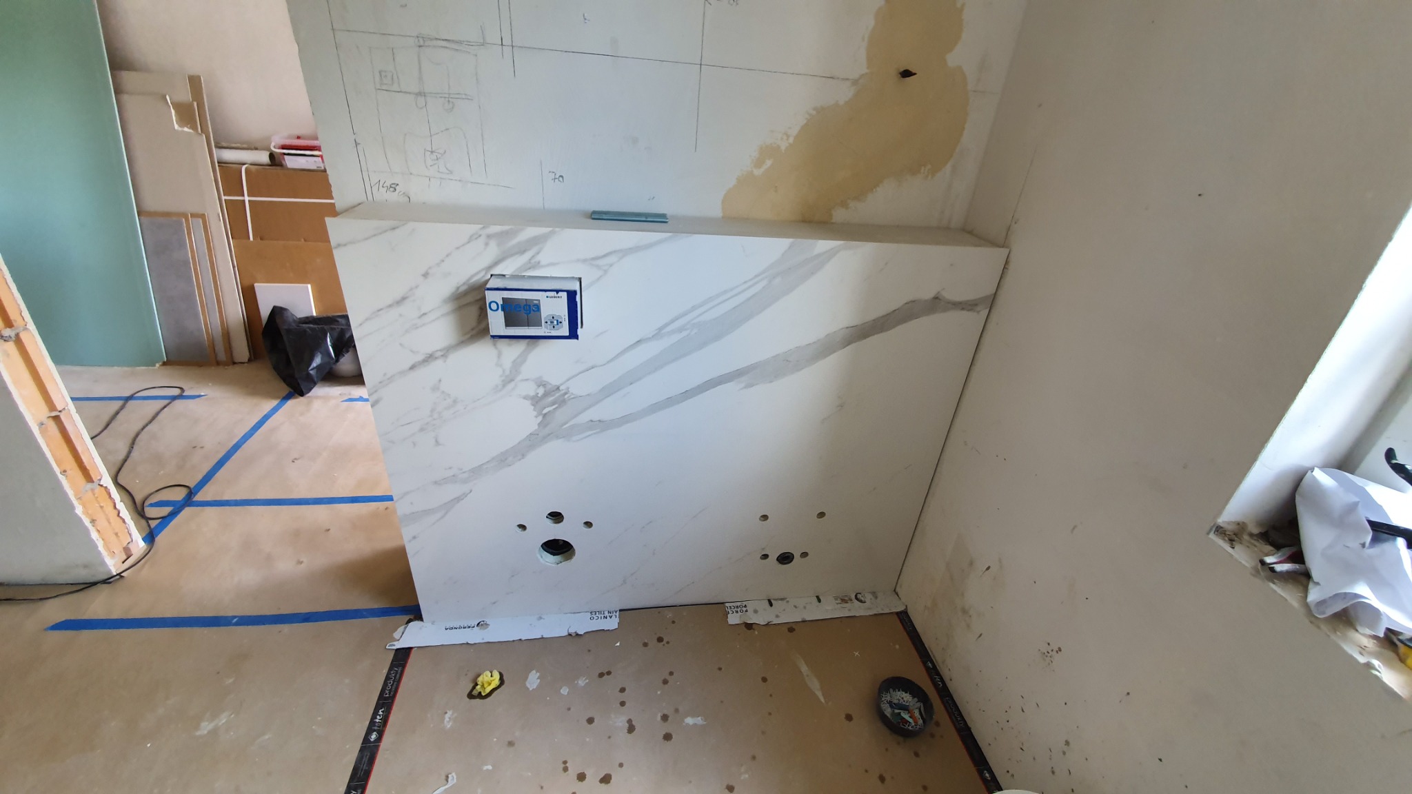 Montaż umywalki z marmurowym blatem w trakcie prac wykończeniowych w Warszawie, widoczne otwory na instalację hydrauliczną i kontroler elektroniczny.