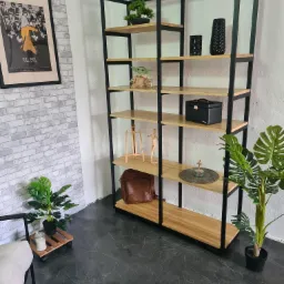 Regał metalowy z drewnianymi półkami, dekorowany roślinami doniczkowymi, figurką Baby Yoda i plakatem filmowym Kill Bill na tle ściany z cegły.