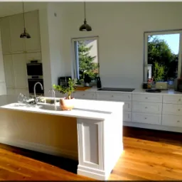 Jasna kuchnia z wyspą i drewnianą podłogą, oświetlona promieniami słońca wpadającymi przez okna z widokiem na zieleń.