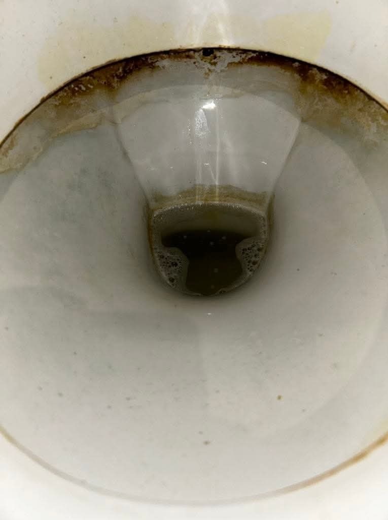 Zanieczyszczona muszla klozetowa z widocznymi osadami i brudną wodą, wymagająca dokładnego wyczyszczenia.