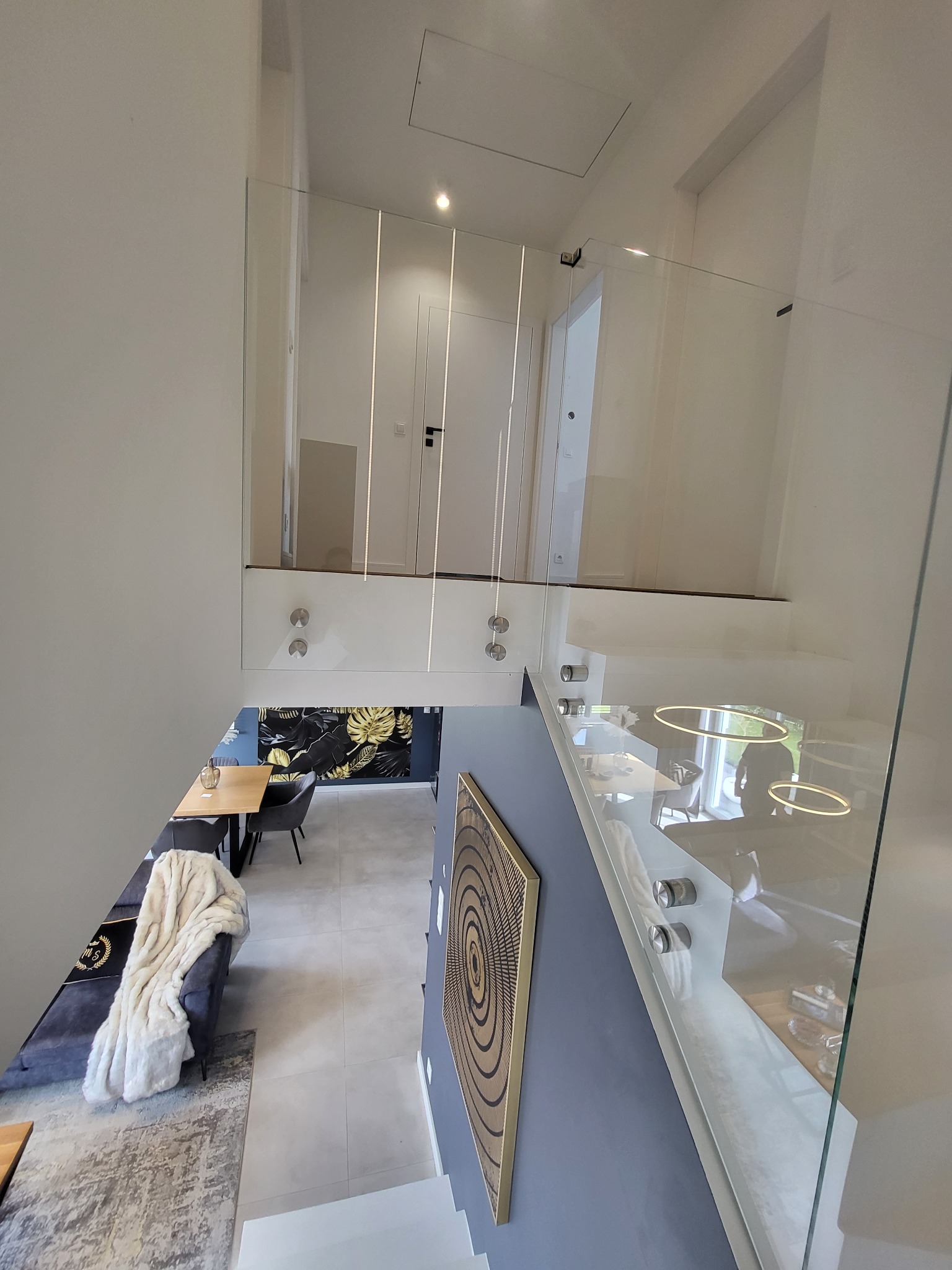 Szklana balustrada na schodach w nowoczesnym wnętrzu, widok z góry, minimalistyczny design z elementami dekoracyjnymi w tle.