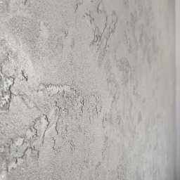 Grudziądz - Szara ściana z dekoracyjną fakturą imitującą kamień, wykonana techniką szpachlowania z delikatnym połyskiem.