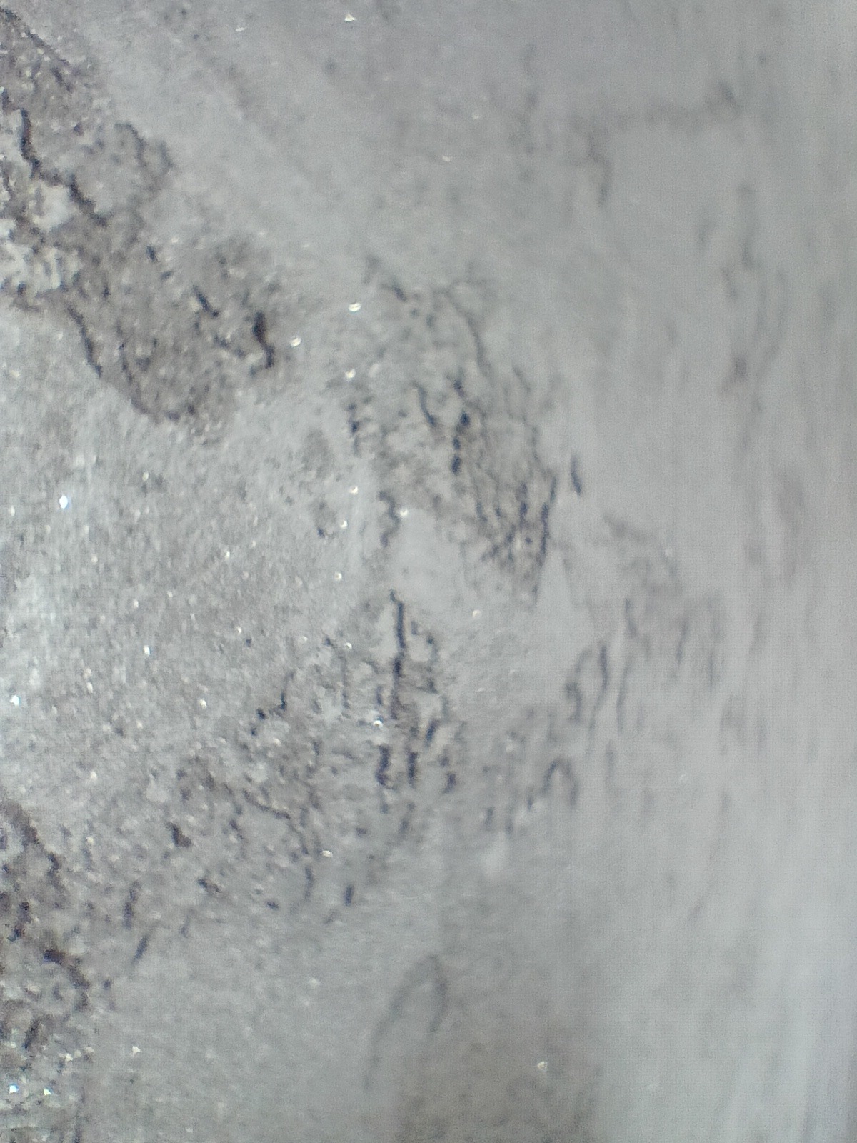 Szare, nierównomierne tło z widocznymi drobnymi plamkami i teksturą przypominającą niedokładne wykończenie ściany lub sufitu.