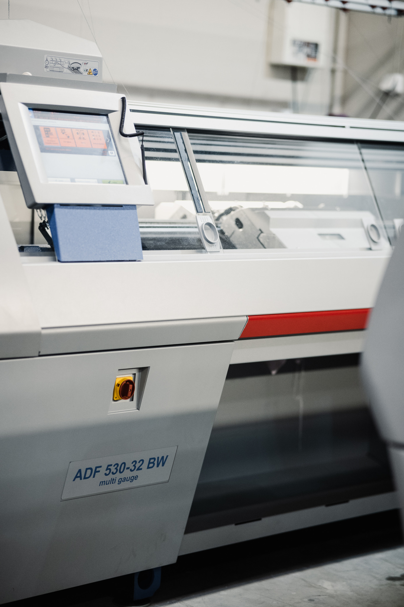 Profesjonalna, przemysłowa maszyna dziewiarska ADF 530-32 BW z panelem sterowania, widoczna przez osłonę maszyny część procesu tworzenia dzianiny.