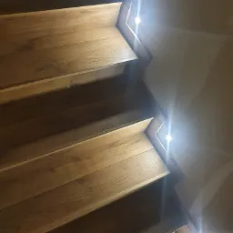 Drewniane schody z wbudowanym oświetleniem LED, widok z góry, ciepła barwa światła.