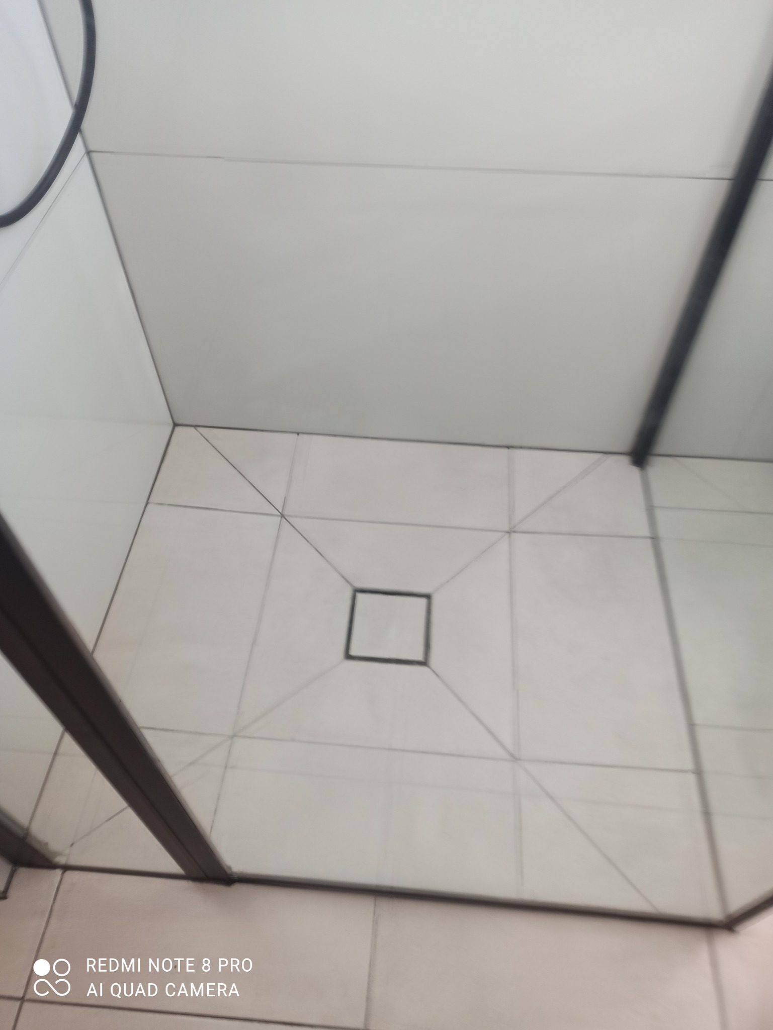 Białe płytki podłogowe w kabinie prysznicowej z odpływem liniowym w kształcie kwadratu, widok z góry.