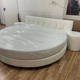 Łóżko tapicerowane z zagłówkiem oraz stolikami nocnymi.