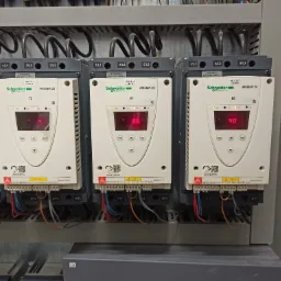 Panel sterowania przemysłowego z trzema modułami Schneider Electric Altistart 22, każdy z wyświetlaczem LED pokazującym różne wartości (41, 66, 40), podłączonymi kablami i oznaczonymi zaciskami.
