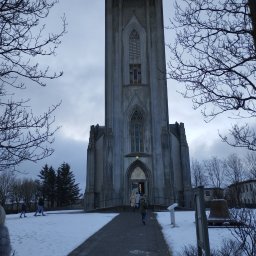 A.L. serwis budowlany - Monumentalna, betonowa konstrukcja sakralna z wysoką wieżą i gotyckimi oknami, widziana z dołu w zimowej scenerii z ludźmi wchodzącymi do środka.