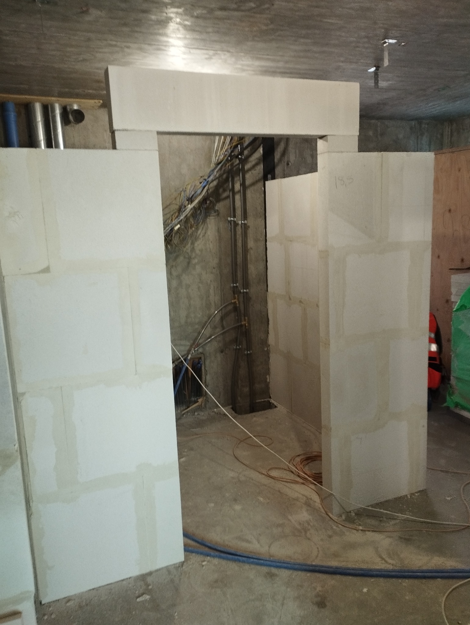 Wewnętrzna konstrukcja ścian działowych z betonu komórkowego z widocznymi instalacjami elektrycznymi i hydraulicznymi w surowym stanie.