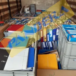 Wnętrze furgonetki wypełnionej po brzegi szarymi plastikowymi pojemnikami i kartonami, w których znajdują się segregatory z dokumentami o różnych kolorach, przygotowane do transportu.