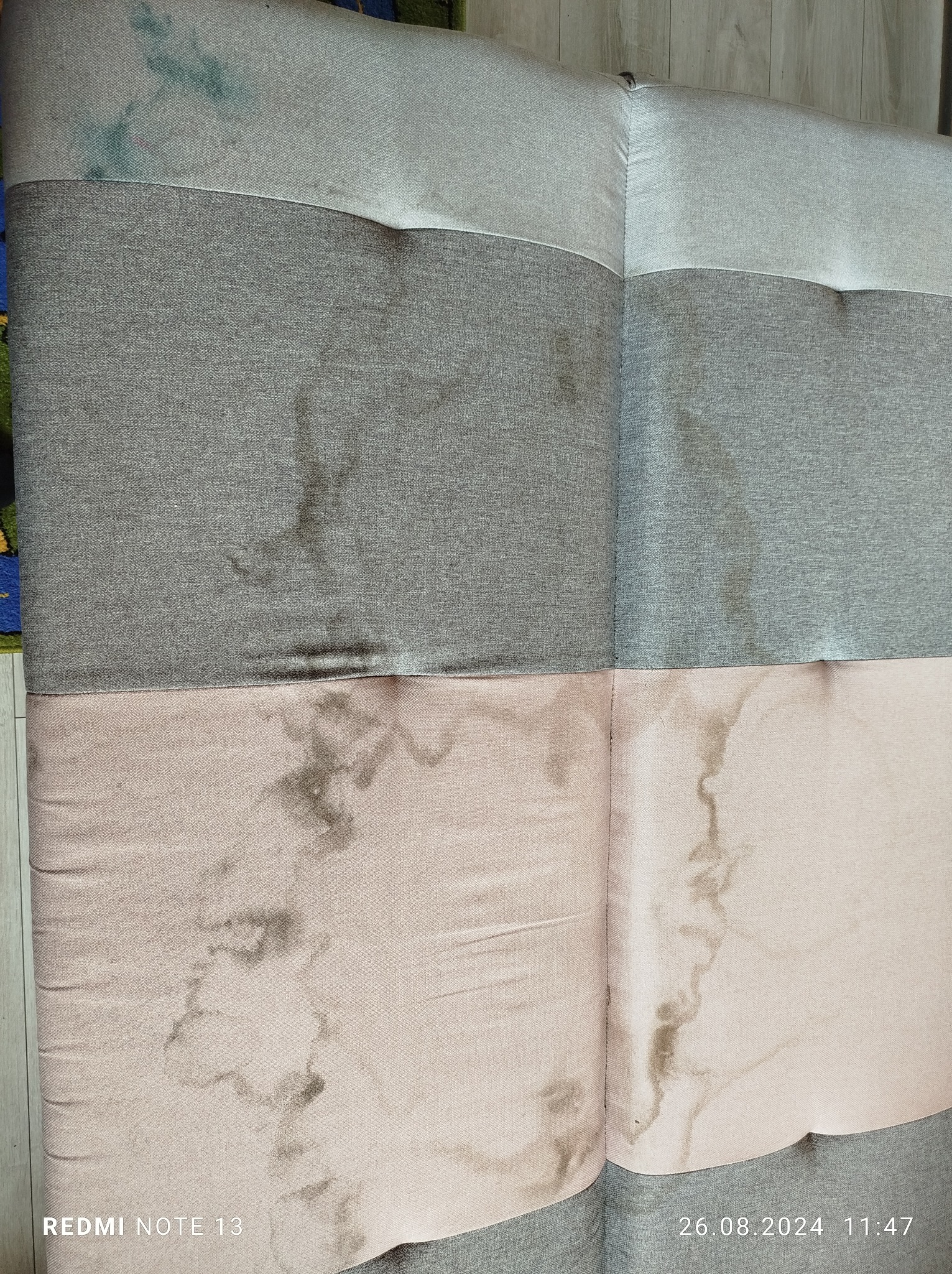 Brudna, dwukolorowa tapicerka meblowa z widocznymi plamami i zaciekami, wymagająca odświeżenia.