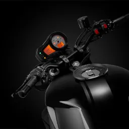 Czarny motocykl z widocznym kokpitem, kierownicą i zbiornikiem paliwa w studio z ciemnym tłem.