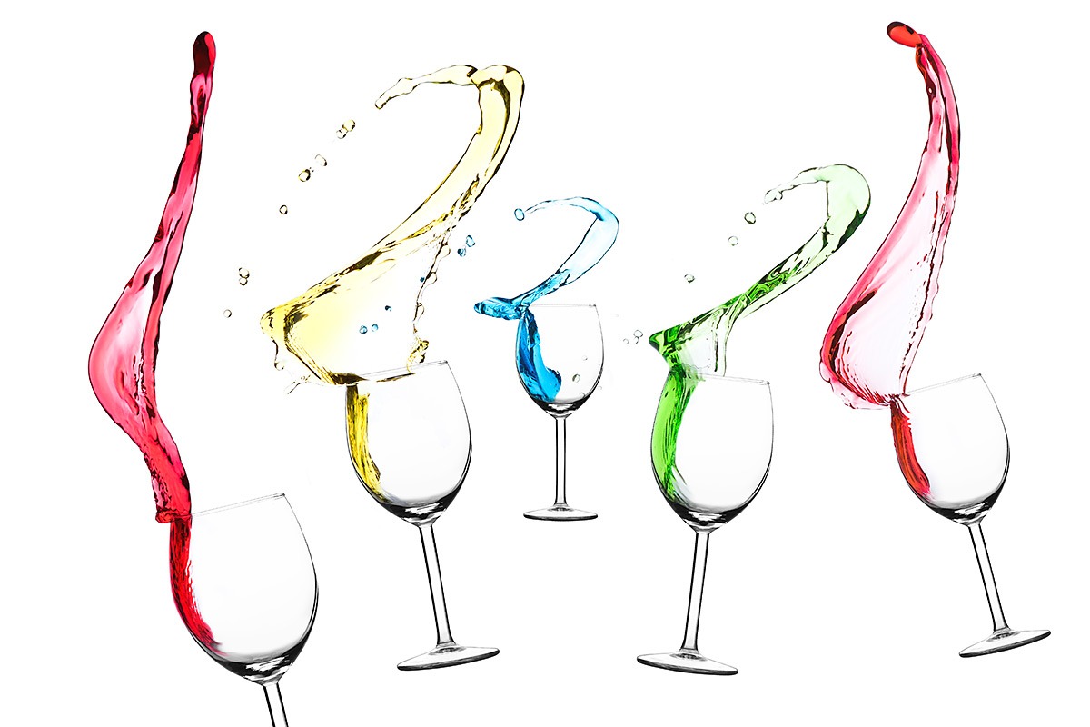 Pięć kieliszków z wylewającymi się kolorowymi płynami: czerwonym, żółtym, niebieskim i zielonym, na białym tle. Płyny tworzą dynamiczne kształty w powietrzu.