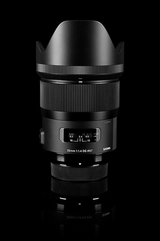 Obiektyw Sigma 35mm f/1.4 DG HSM Art na czarnym tle z widocznym pierścieniem ostrości i osłoną przeciwsłoneczną.
