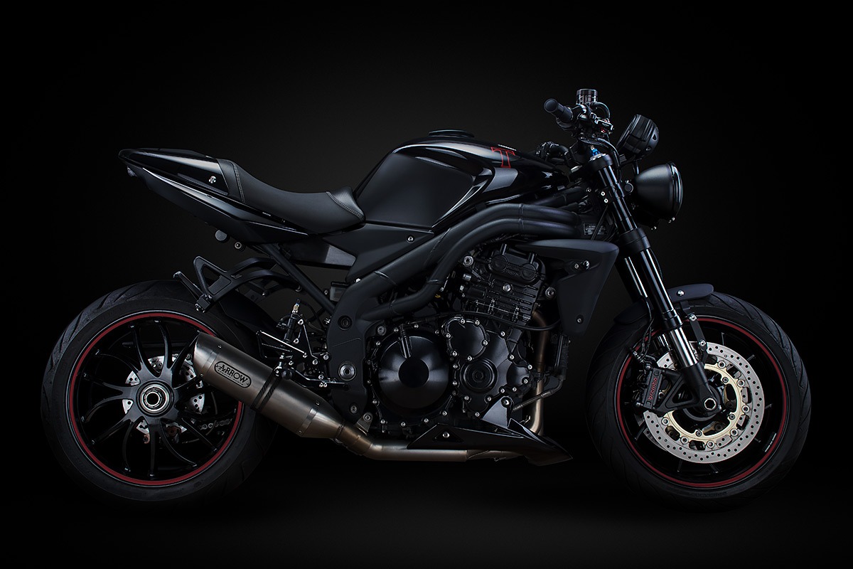 Czarny motocykl typu naked bike z wydechem Arrow, oponami z czerwonym paskiem, zaprezentowany na ciemnym tle.