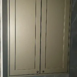 Zamknięta szafka łazienkowa w kolorze oliwkowym, z dwoma drzwiczkami i okrągłymi uchwytami, zamontowana nad spłuczką wbudowaną w ścianę wykończoną szarym marmurem.