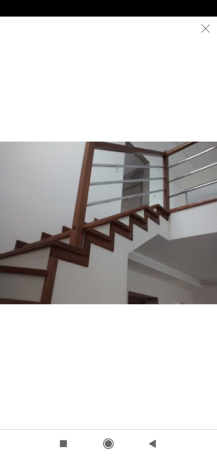 Wnętrze z drewnianymi schodami z metalową balustradą, widok z dołu, oświetlenie dzienne.